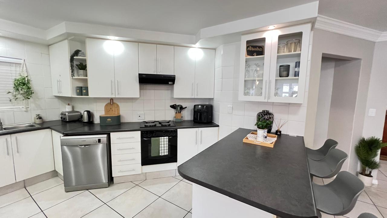 White kitchen with breakfast counter, oven, hob and dishwasher