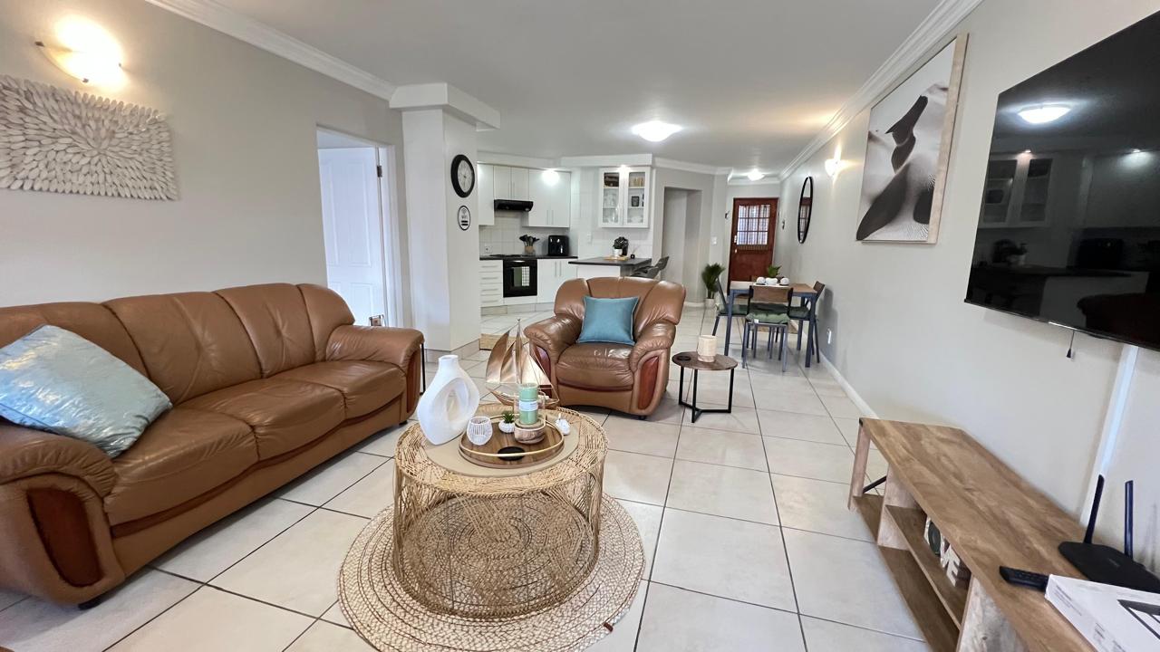 Open-plan living room with leather seating, a woven coffee table and dining area