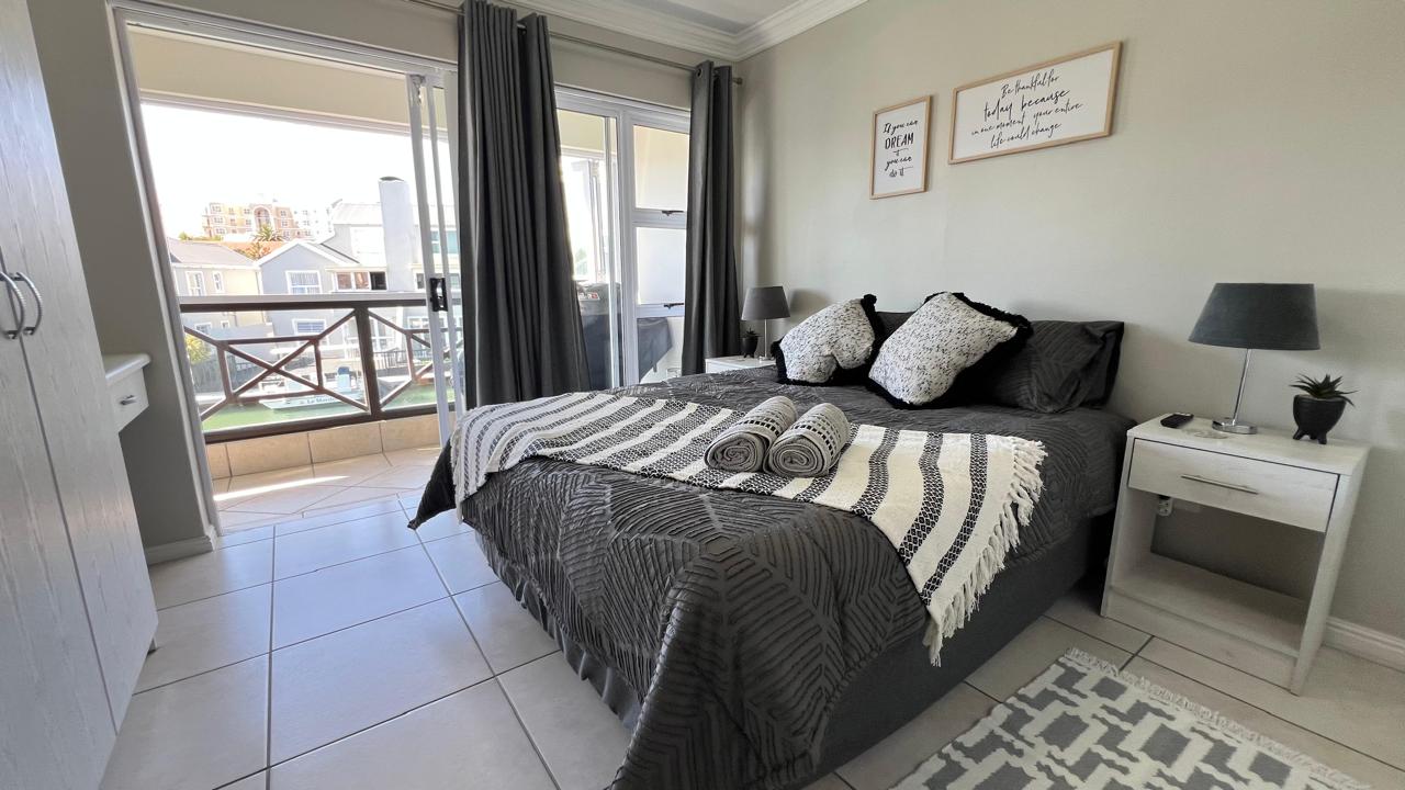 Queen-size bed with charcoal bedding and doors opening towards the canal balcony