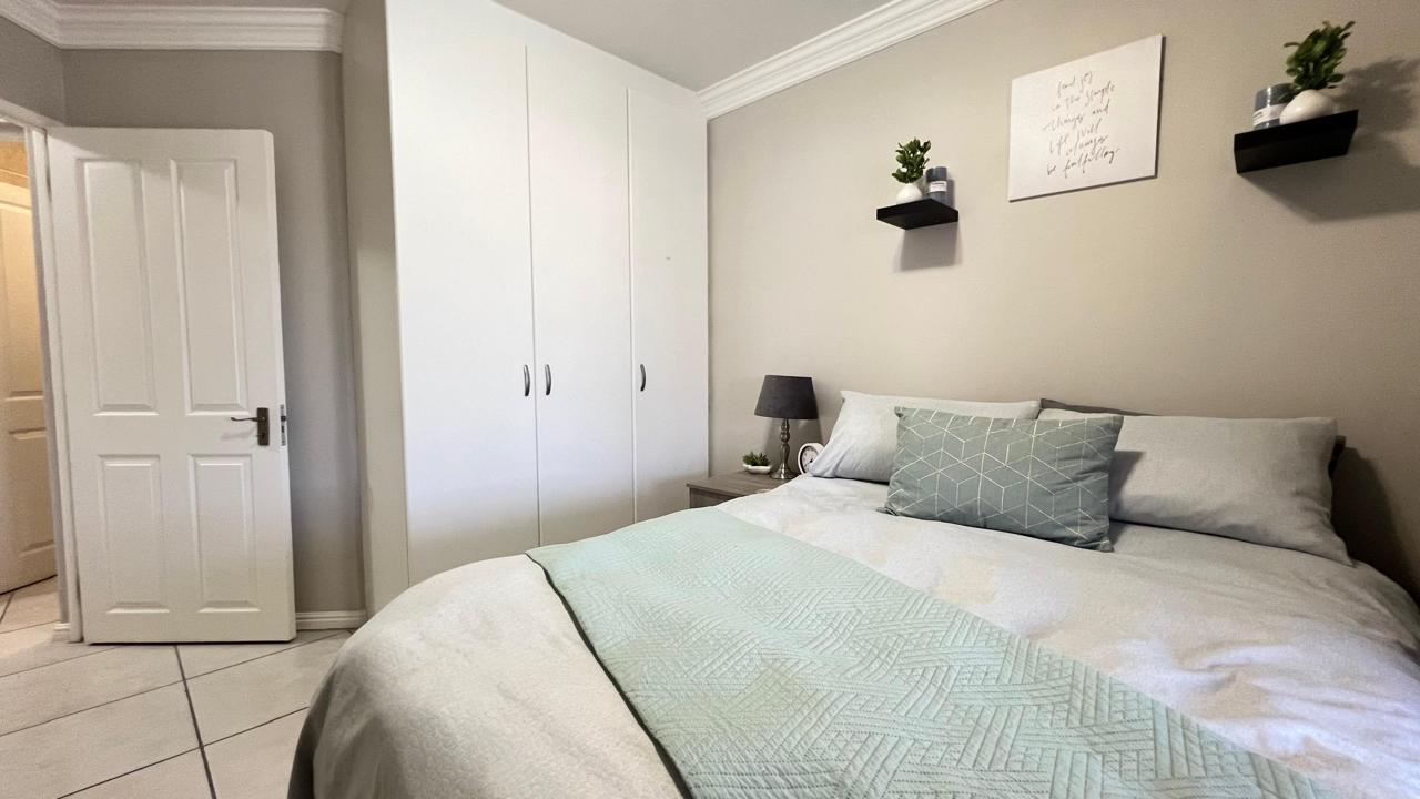 Double bedroom with soft sage bedding and white fitted wardrobes