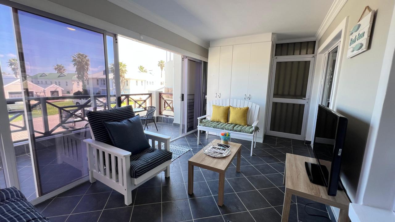 Second patio with white wooden seating, blue and yellow cushions and sliding glass doors