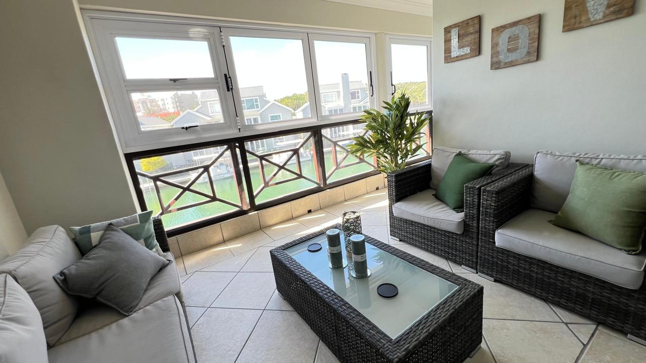 Wicker seating and green cushions on the balcony overlooking the canal